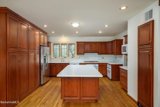 kitchen featuring light wood finished floors, visible vents, white appliances, and light countertops