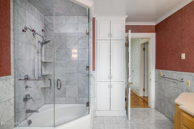 full bathroom with combined bath / shower with glass door, marble finish floor, tile walls, and ornamental molding