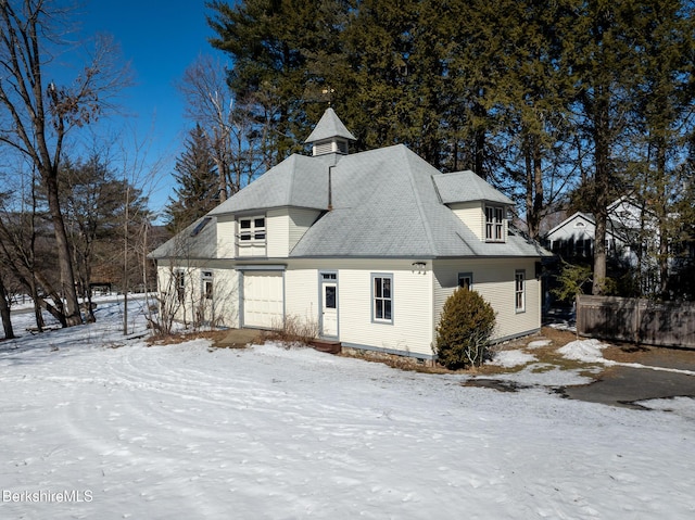 snow covered property with a garage and fence