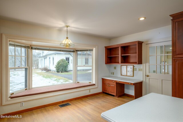 kitchen with visible vents, open shelves, light wood finished floors, light countertops, and built in study area