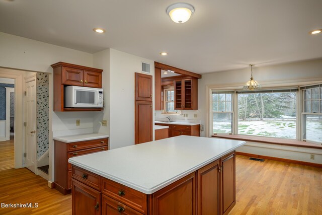 kitchen with light countertops, white microwave, visible vents, and light wood-type flooring