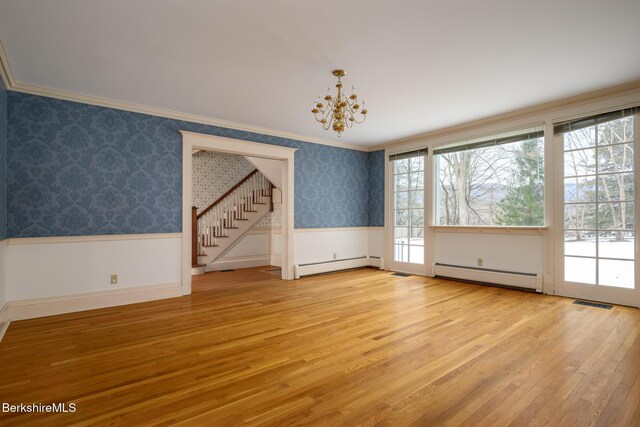 empty room with wallpapered walls, a wainscoted wall, and a baseboard heating unit