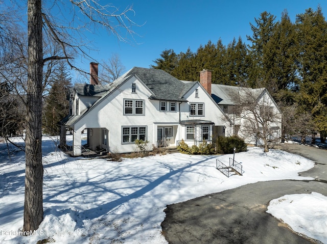 view of front of house with stucco siding and a chimney