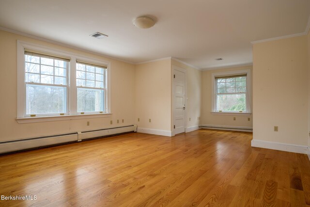 empty room featuring visible vents, a baseboard heating unit, ornamental molding, baseboard heating, and light wood-style floors