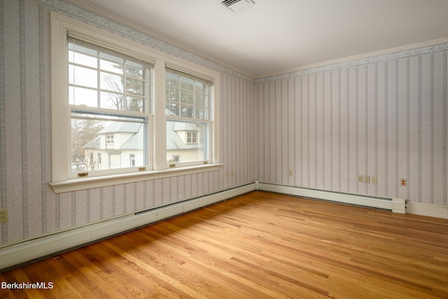 spare room with wallpapered walls, wood finished floors, visible vents, and a baseboard radiator