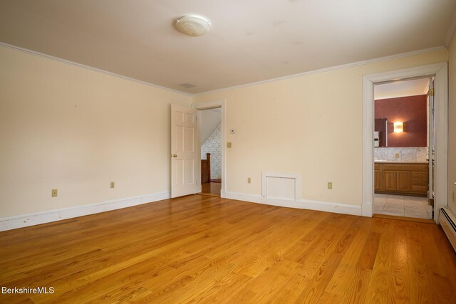 unfurnished bedroom featuring baseboards, light wood-type flooring, ornamental molding, ensuite bath, and a baseboard radiator