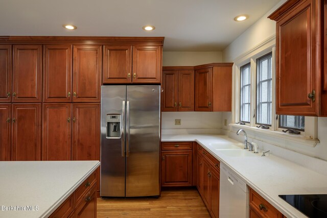 kitchen with black electric stovetop, dishwasher, light countertops, stainless steel refrigerator with ice dispenser, and a sink