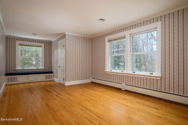 empty room with wallpapered walls, crown molding, and light wood-style flooring