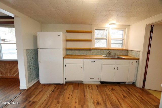 kitchen with a sink, white appliances, butcher block countertops, and wood finished floors