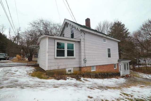 view of snowy exterior featuring a chimney