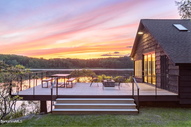 wooden terrace with a water view and a fire pit