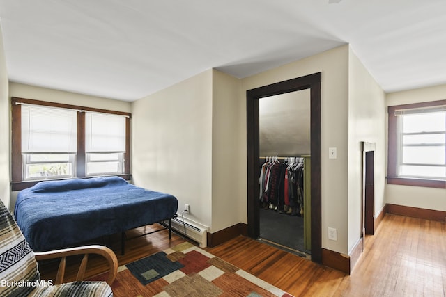 bedroom with baseboards, multiple windows, a closet, and wood finished floors