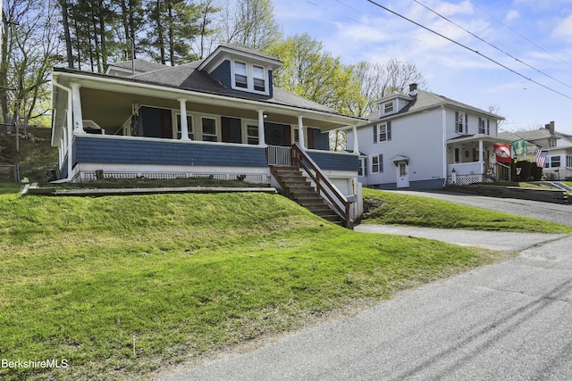 bungalow-style home with covered porch, a garage, a shingled roof, aphalt driveway, and a front lawn