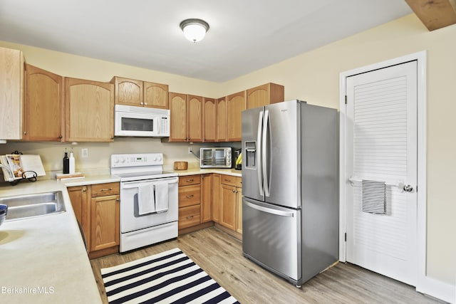 kitchen featuring light wood-style flooring, a toaster, white appliances, a sink, and light countertops