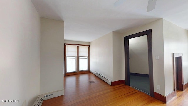 empty room featuring baseboards, baseboard heating, ceiling fan, and wood finished floors