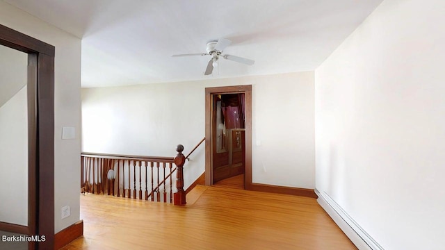hall featuring baseboards, baseboard heating, an upstairs landing, and wood finished floors