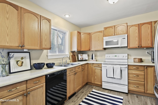 kitchen featuring white appliances, light countertops, a sink, and light wood-style floors