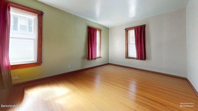 empty room featuring baseboards, plenty of natural light, and wood finished floors