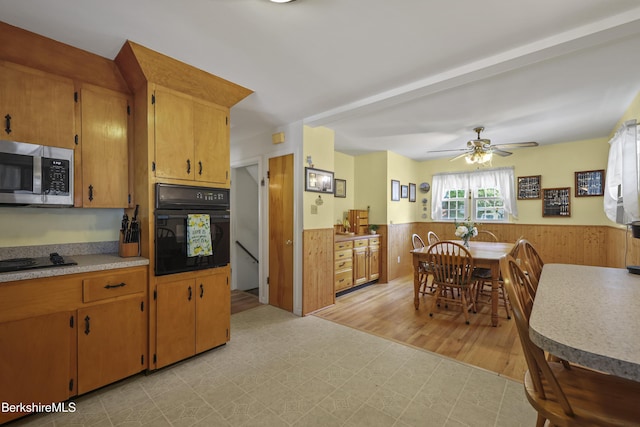 17 Jeffrey Dr, Pittsfield, MA 01201 - kitchen with black appliances, wainscoting, light flooring, ceiling fan, and wooden walls