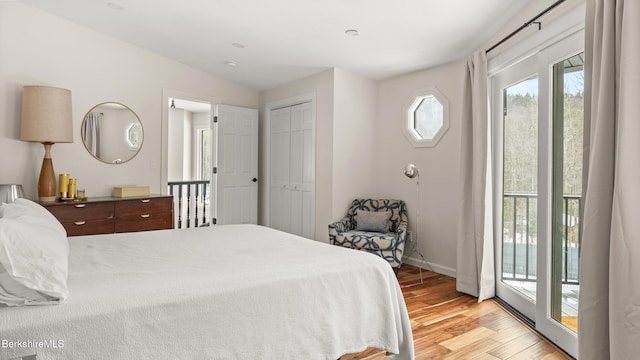 bedroom with baseboards, vaulted ceiling, access to outside, light wood-style floors, and a closet