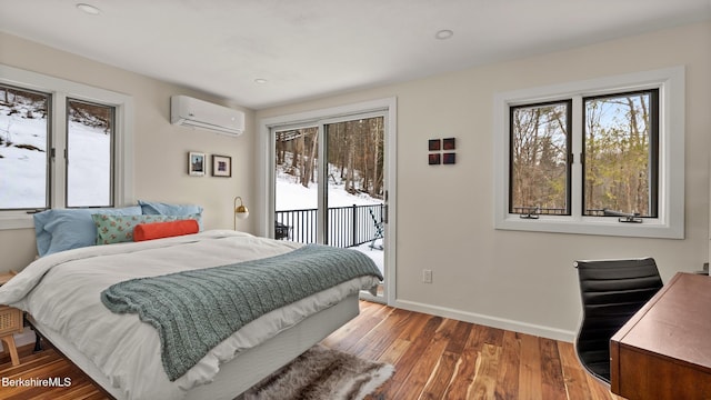 bedroom featuring access to exterior, multiple windows, an AC wall unit, and wood finished floors