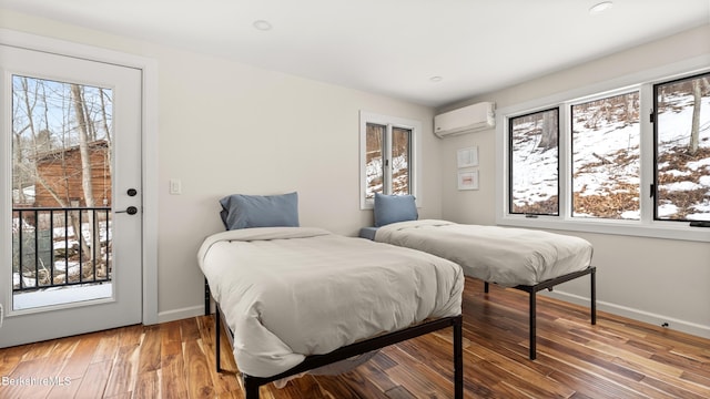 bedroom with light wood-style floors, an AC wall unit, and baseboards