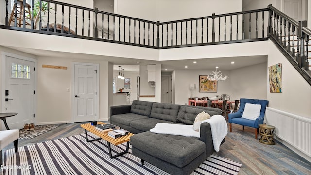 living room with stairs, a high ceiling, wood finished floors, and an inviting chandelier