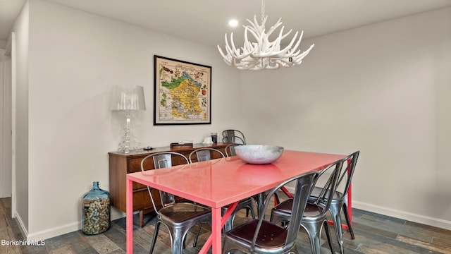 dining room featuring dark wood finished floors, baseboards, and an inviting chandelier