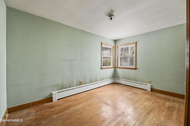 unfurnished room featuring wood-type flooring and a baseboard heating unit