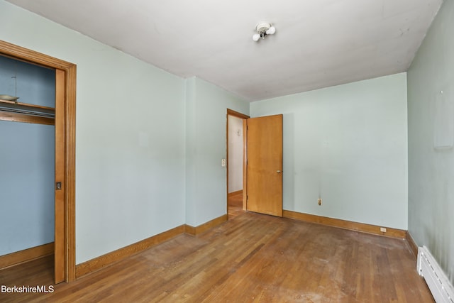 unfurnished bedroom with a baseboard radiator, a closet, and hardwood / wood-style flooring