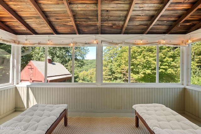 sunroom / solarium with wood ceiling, plenty of natural light, and lofted ceiling with beams