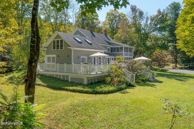 back of house featuring a wooden deck, a sunroom, and a yard