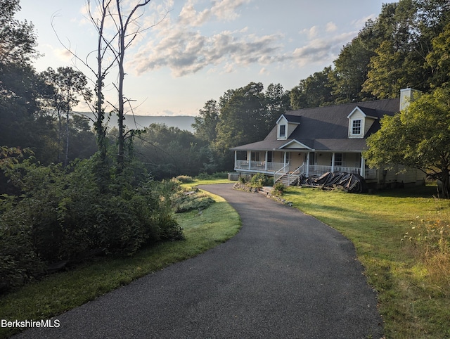 country-style home featuring aphalt driveway, a front yard, and covered porch