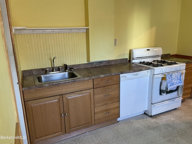 kitchen featuring white appliances, light floors, a sink, dark countertops, and brown cabinets