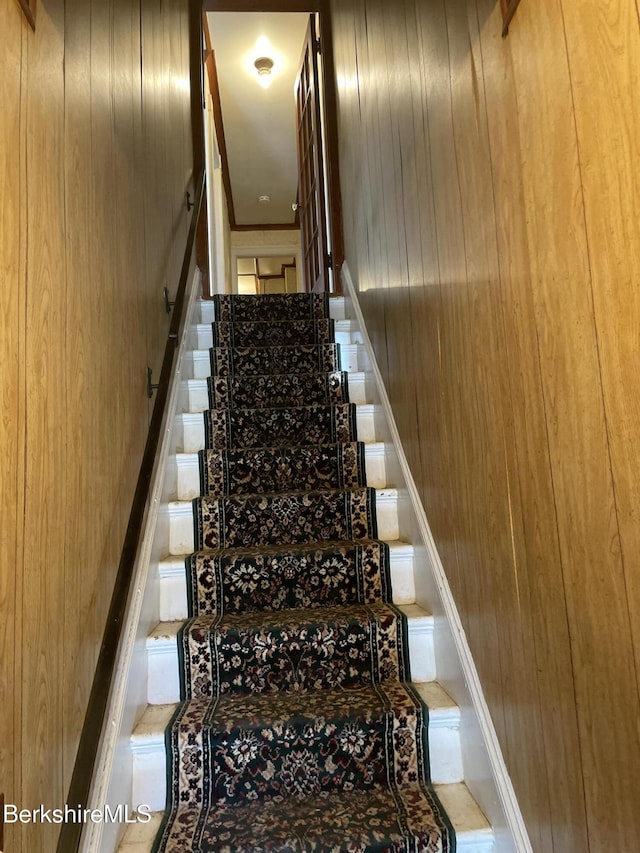 stairs with wood walls and tile patterned flooring