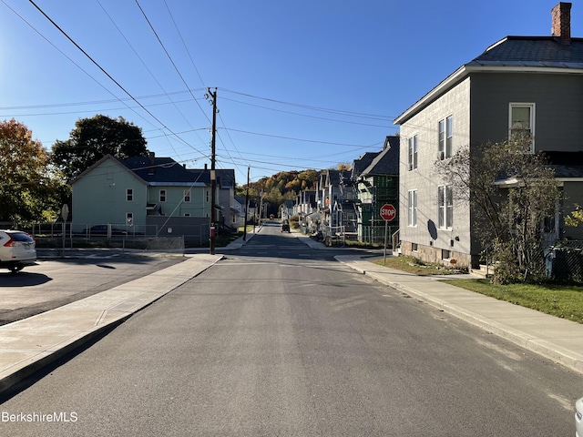 view of street with sidewalks, a residential view, curbs, and traffic signs