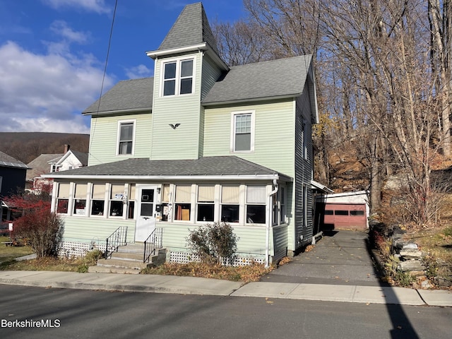 victorian home with a detached garage, an outbuilding, and roof with shingles