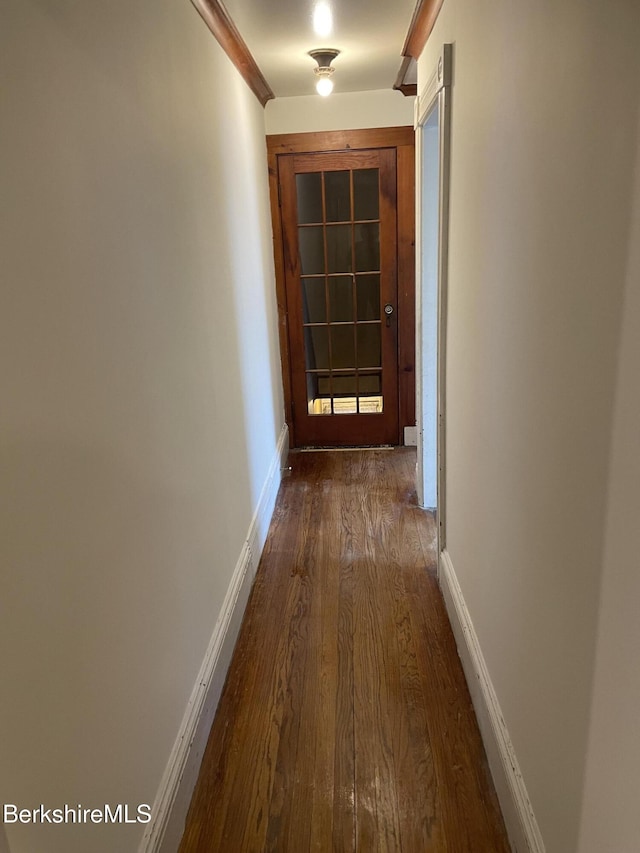 corridor featuring dark wood finished floors and baseboards