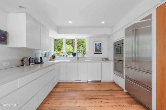 kitchen featuring light countertops, white cabinets, modern cabinets, stainless steel appliances, and a sink