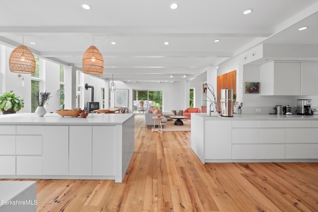 kitchen featuring modern cabinets, light wood-style flooring, white cabinetry, light countertops, and beam ceiling
