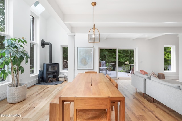 dining area featuring recessed lighting, a wood stove, light wood-style flooring, and beamed ceiling