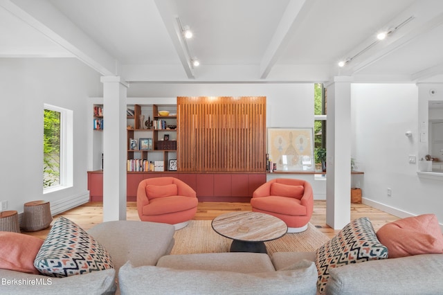 living area featuring baseboards, beamed ceiling, and wood finished floors