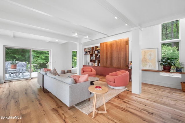 living area featuring light wood-style flooring, ornate columns, and beamed ceiling
