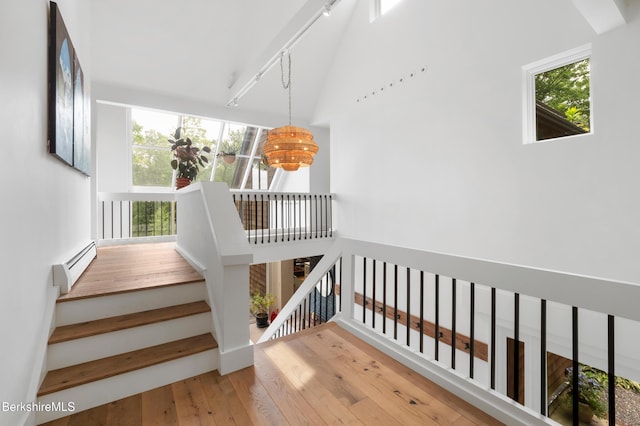 stairway with a chandelier, hardwood / wood-style flooring, and a baseboard heating unit