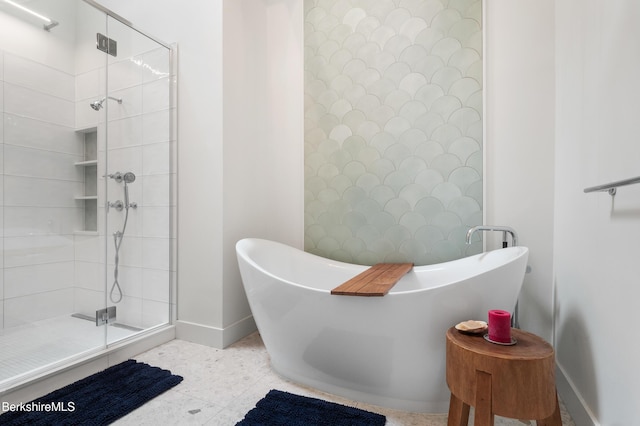full bathroom featuring a stall shower, a freestanding tub, and baseboards