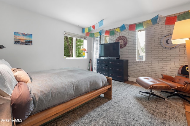 bedroom with brick wall and wood finished floors