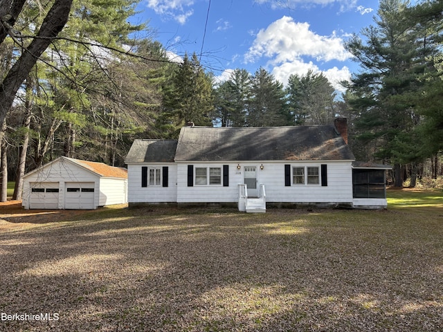 view of front facade featuring a garage, a front lawn, and an outdoor structure