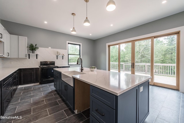 138 Ridge Rd, Worthington, MA 01098 - kitchen featuring black range with electric cooktop, tasteful backsplash, a center island with sink, white cabinetry, and hanging light fixtures
