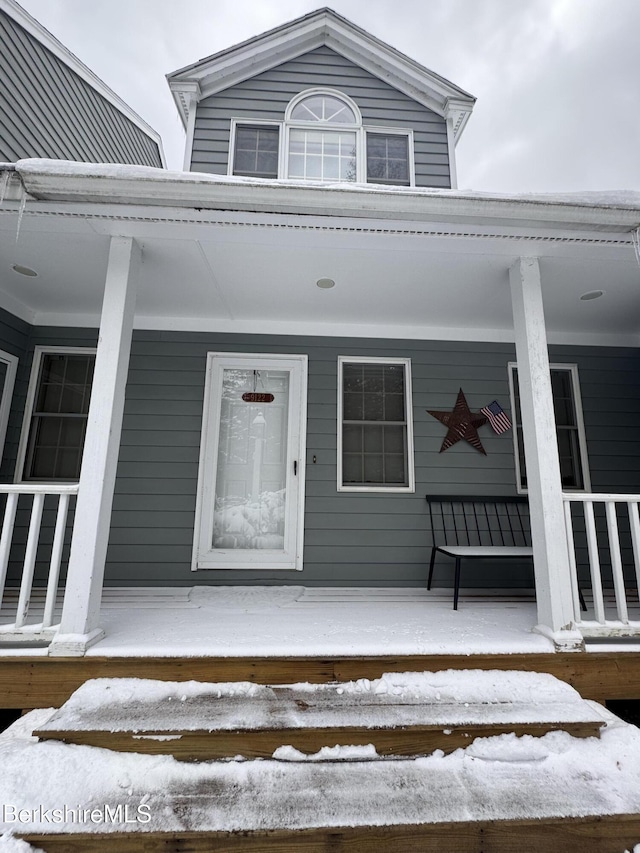 snow covered property entrance with a porch