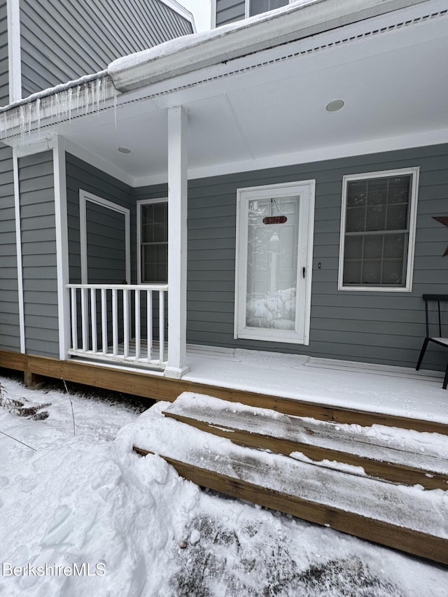 snow covered property entrance with covered porch